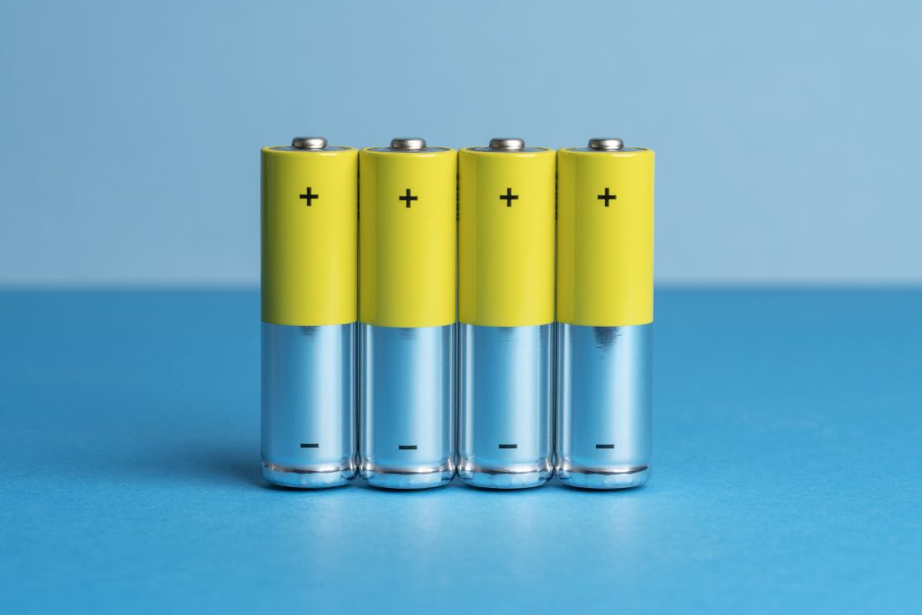 電池_Elevated view of four yellow batteries on a blue colored background